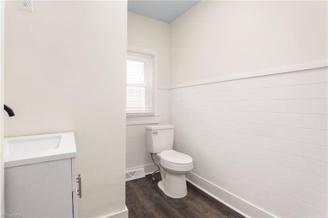 bathroom featuring visible vents, toilet, wood finished floors, wainscoting, and vanity