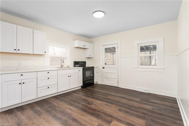 kitchen featuring black electric range, dark wood-type flooring, white cabinets, and a sink