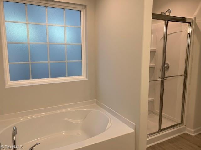 bathroom with hardwood / wood-style flooring and shower with separate bathtub