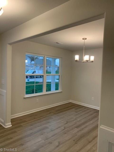 spare room with dark hardwood / wood-style flooring and a notable chandelier