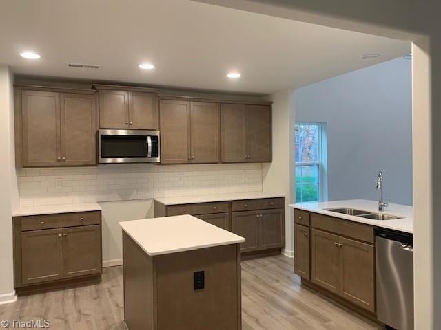 kitchen featuring light wood-type flooring, a center island, stainless steel appliances, and sink