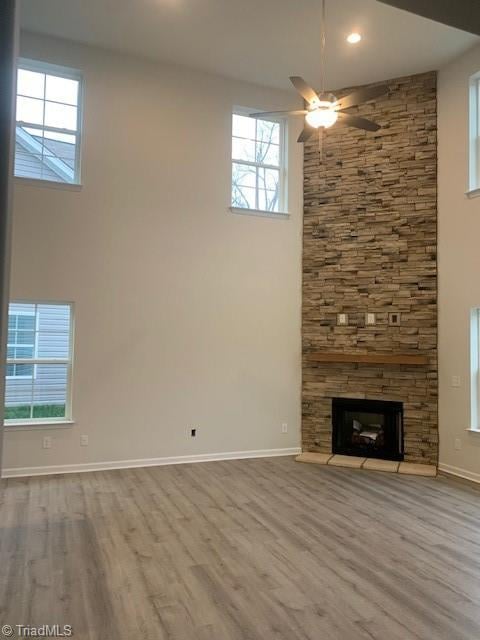 unfurnished living room featuring a fireplace, light hardwood / wood-style flooring, a wealth of natural light, and ceiling fan