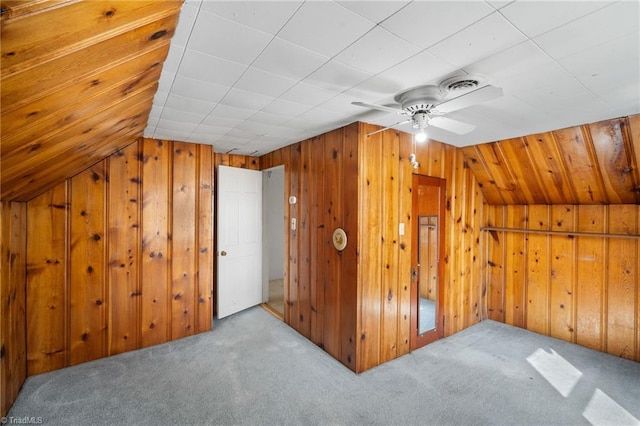 additional living space with lofted ceiling, light colored carpet, and wooden walls