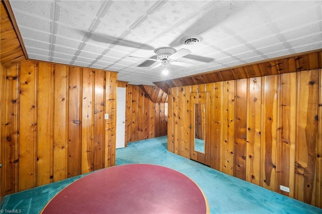 additional living space featuring ceiling fan, light carpet, and wood walls