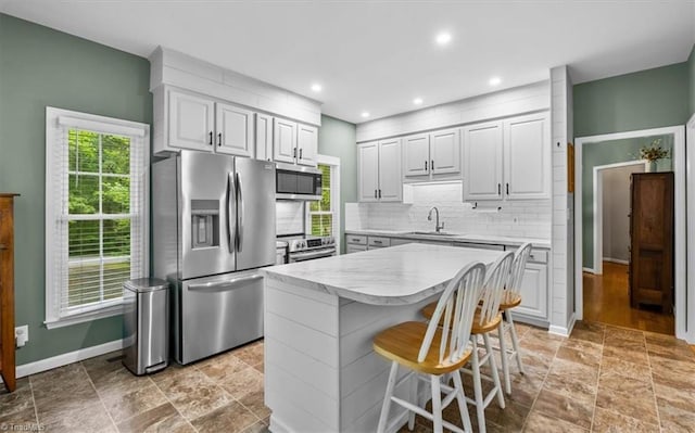 kitchen with baseboards, light countertops, a sink, backsplash, and stainless steel appliances