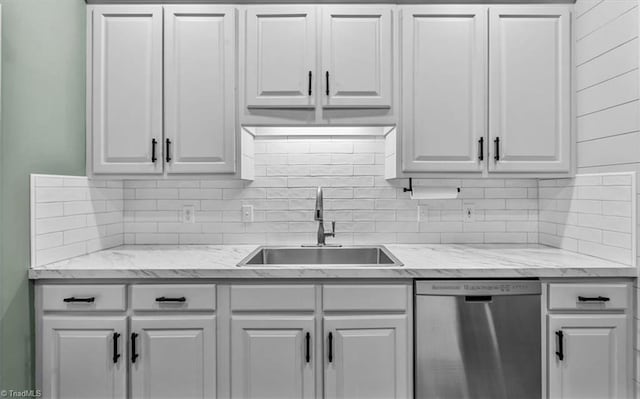 kitchen featuring light stone countertops, white cabinetry, tasteful backsplash, a sink, and dishwasher