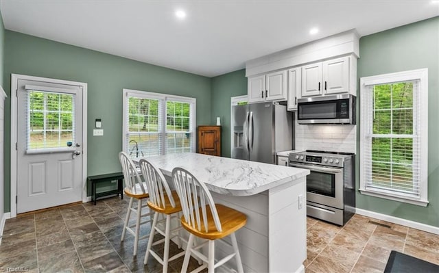 kitchen with plenty of natural light, baseboards, a breakfast bar area, and stainless steel appliances
