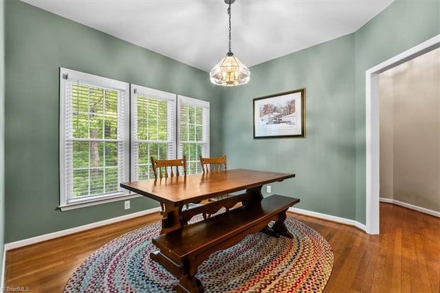 dining space featuring baseboards, a notable chandelier, and wood finished floors