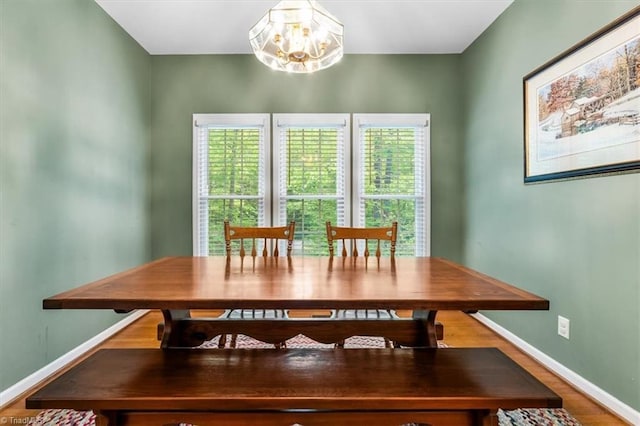 dining area with baseboards, wood finished floors, and a chandelier