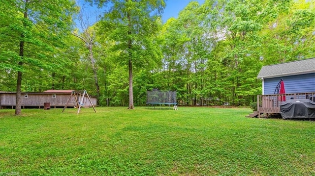 view of yard featuring a trampoline and a deck