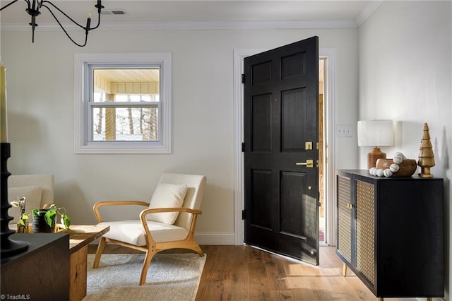 entryway featuring ornamental molding, hardwood / wood-style floors, and an inviting chandelier