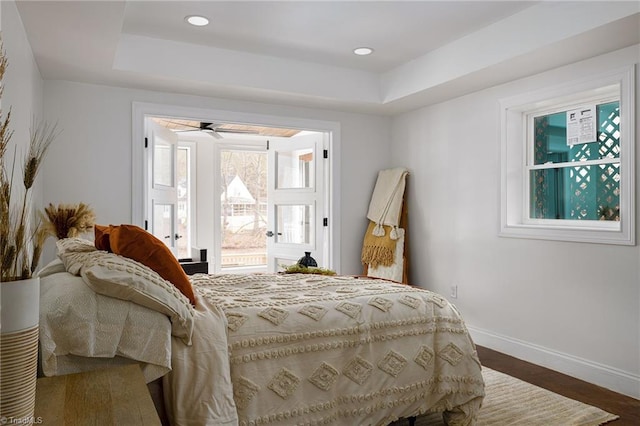 bedroom with dark hardwood / wood-style flooring and a raised ceiling