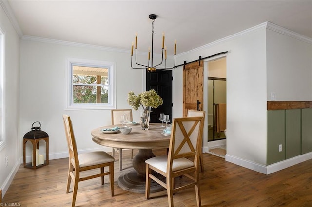 dining room featuring an inviting chandelier, wood-type flooring, ornamental molding, and a barn door