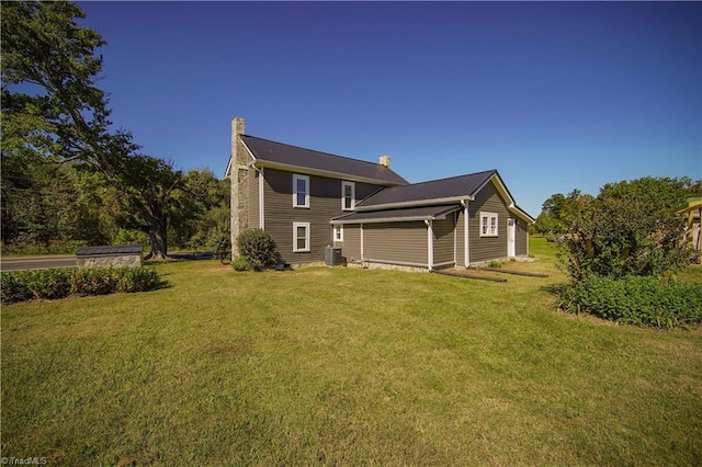 rear view of property featuring a lawn and central AC unit