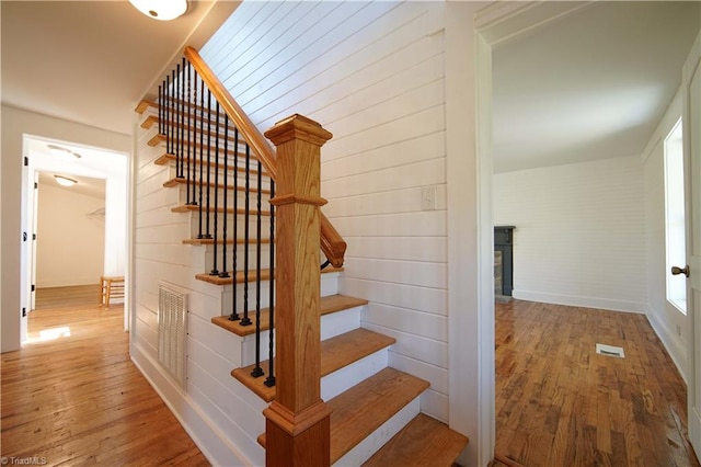 stairway featuring wood-type flooring and wooden walls