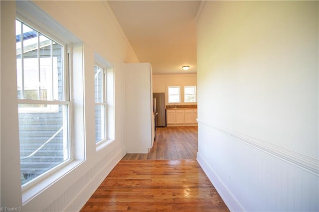 hall with hardwood / wood-style floors, crown molding, and plenty of natural light