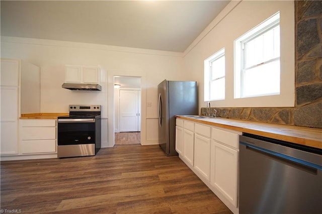 kitchen with white cabinets, appliances with stainless steel finishes, dark hardwood / wood-style floors, crown molding, and butcher block countertops