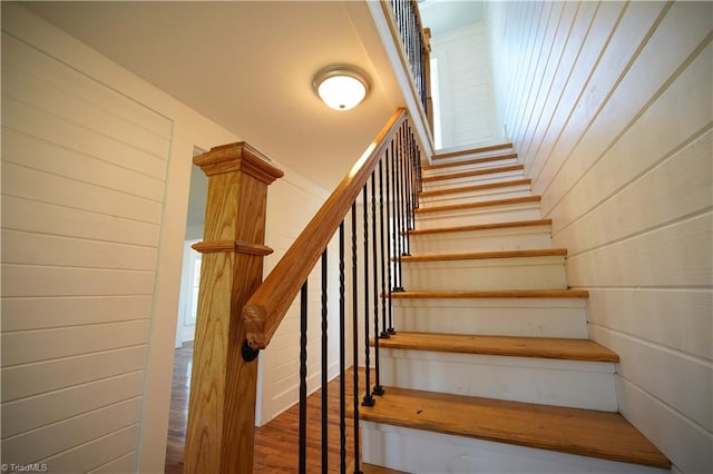 stairway with wood walls and hardwood / wood-style flooring