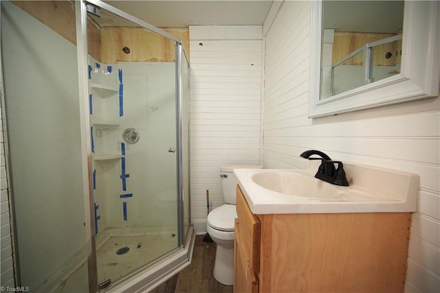 bathroom featuring toilet, wooden walls, hardwood / wood-style floors, vanity, and walk in shower