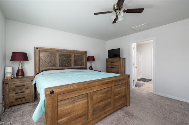 bedroom with ceiling fan, light colored carpet, and ensuite bath