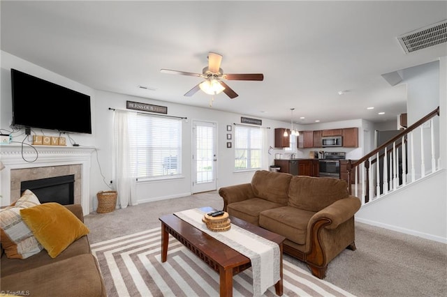 carpeted living room featuring a fireplace and ceiling fan