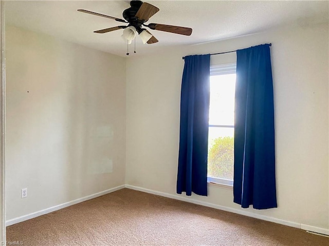 carpeted spare room featuring a wealth of natural light and ceiling fan