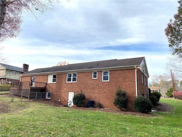 rear view of house featuring a wooden deck and a lawn