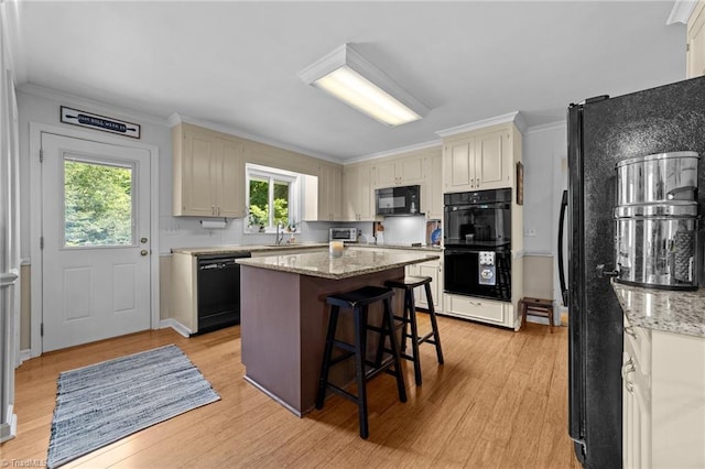 1805 Guilford College Rd, Jamestown, NC 27282 - kitchen featuring black appliances, healthy amount of natural light, light wood-style floors, a breakfast bar, and crown molding