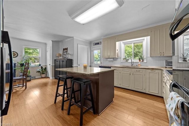 1805 Guilford College Rd, Jamestown, NC 27282 - kitchen featuring a sink, a kitchen island, light wood-style flooring, and a breakfast bar area