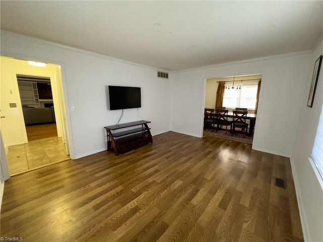 unfurnished living room with crown molding, a notable chandelier, and hardwood / wood-style flooring