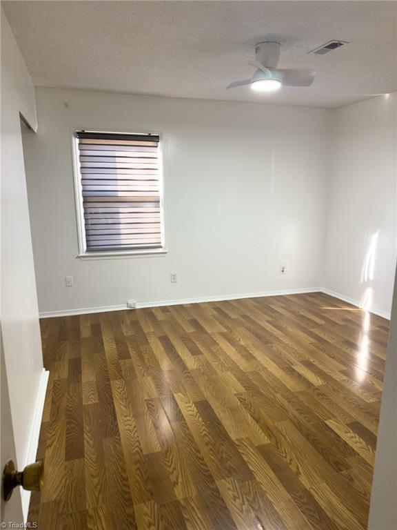 spare room with a textured ceiling, dark hardwood / wood-style floors, and ceiling fan