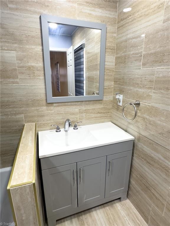 bathroom with wood-type flooring, vanity, and tile walls