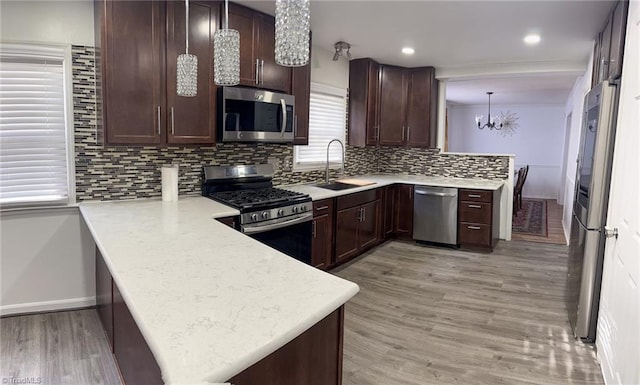 kitchen featuring pendant lighting, sink, kitchen peninsula, stainless steel appliances, and a chandelier