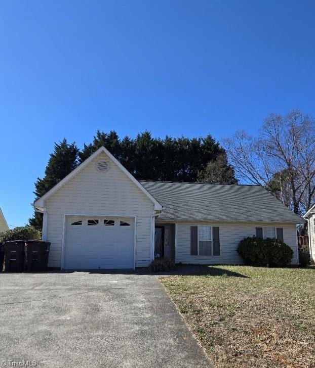 ranch-style house featuring a garage, aphalt driveway, and a front lawn