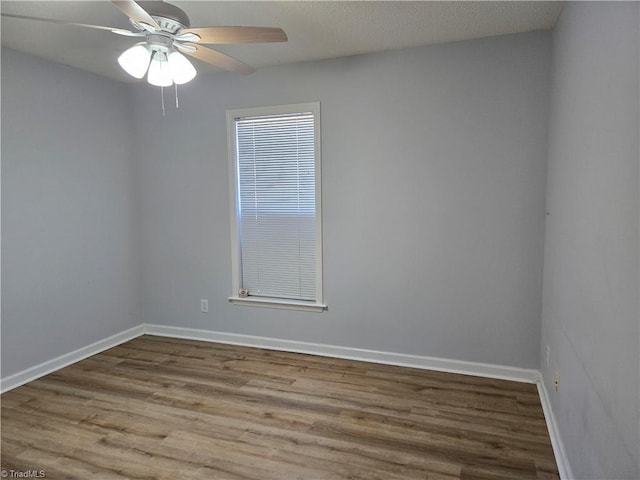 spare room featuring ceiling fan, baseboards, and wood finished floors