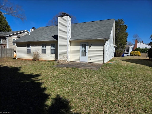 rear view of property featuring a patio area, a chimney, and a lawn