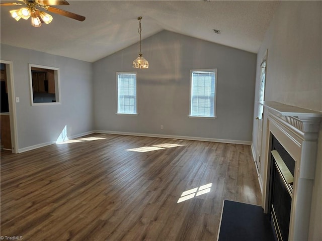 unfurnished living room with lofted ceiling, dark wood-style flooring, plenty of natural light, and baseboards