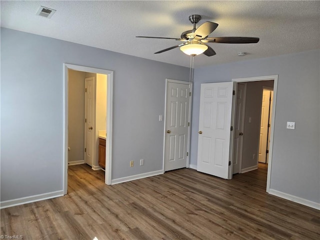 unfurnished bedroom featuring visible vents, a textured ceiling, baseboards, and wood finished floors