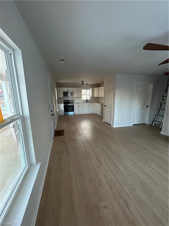 unfurnished living room with ceiling fan, plenty of natural light, and hardwood / wood-style floors