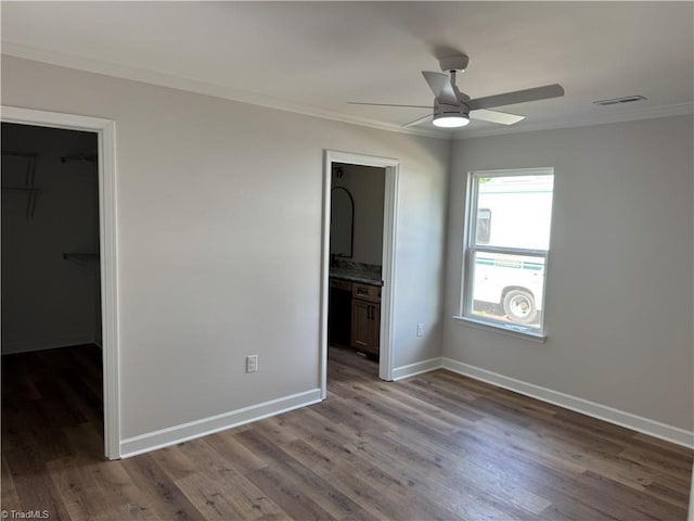 2322 Fernwood Dr, Greensboro, NC 27408 - unfurnished bedroom with a walk in closet, ornamental molding, wood finished floors, baseboards, and a closet