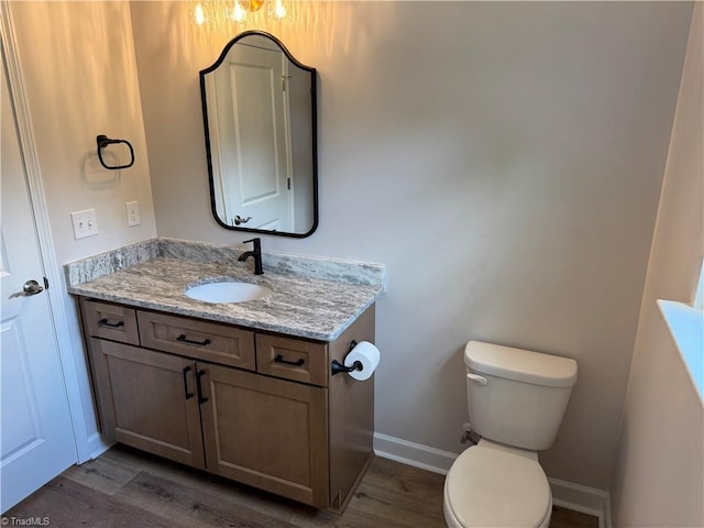 2322 Fernwood Dr, Greensboro, NC 27408 - bathroom with wood finished floors, toilet, vanity, and baseboards
