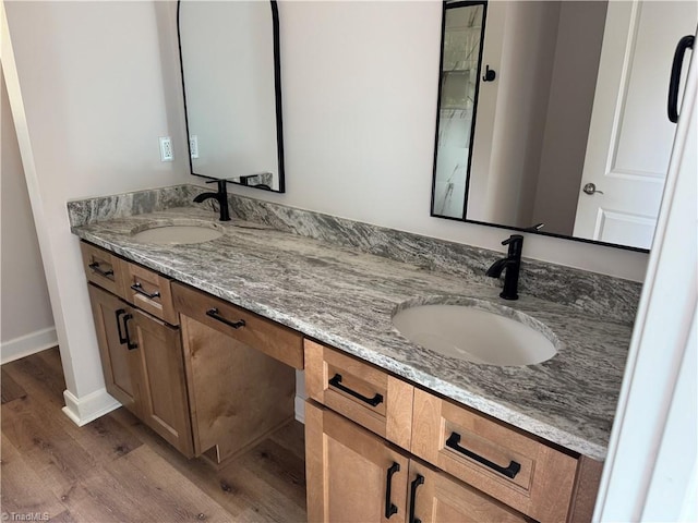 2322 Fernwood Dr, Greensboro, NC 27408 - full bathroom featuring wood finished floors, double vanity, and baseboards