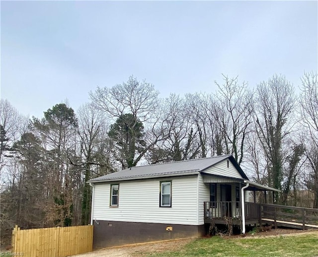 view of side of home with crawl space, metal roof, and fence