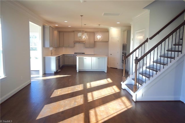 kitchen with dark hardwood / wood-style flooring, ornamental molding, pendant lighting, a chandelier, and a kitchen island