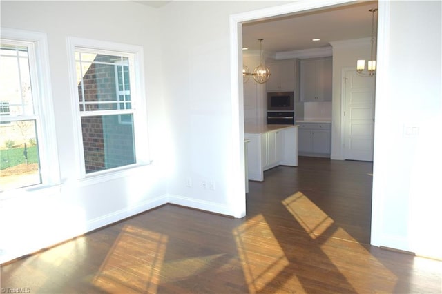 unfurnished room featuring ornamental molding, dark hardwood / wood-style floors, and a notable chandelier