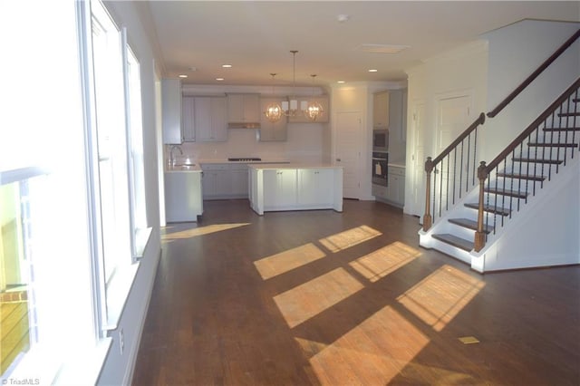 kitchen featuring backsplash, dark wood-type flooring, pendant lighting, an inviting chandelier, and a kitchen island