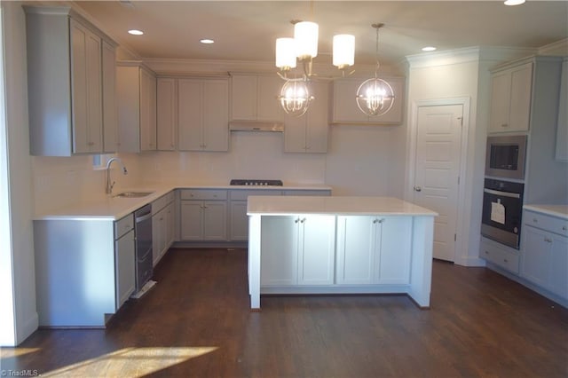 kitchen featuring appliances with stainless steel finishes, sink, a notable chandelier, a kitchen island, and hanging light fixtures