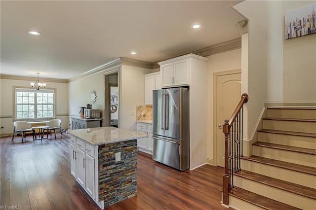 kitchen featuring freestanding refrigerator, ornamental molding, light stone countertops, white cabinets, and a chandelier