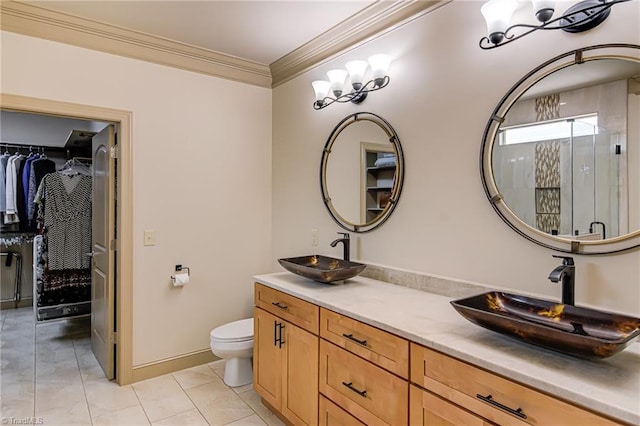 bathroom featuring crown molding, a sink, toilet, a notable chandelier, and a spacious closet