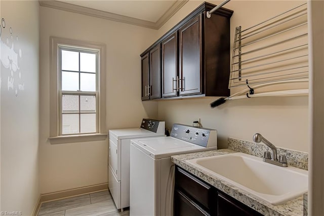 washroom featuring cabinet space, a sink, baseboards, ornamental molding, and washer and dryer